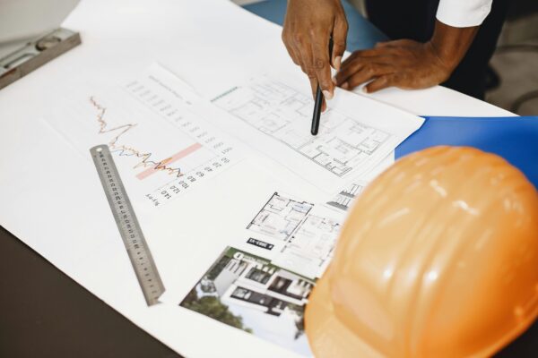 Architect analyzing building blueprints with tools on a desk, showcasing planning and design.